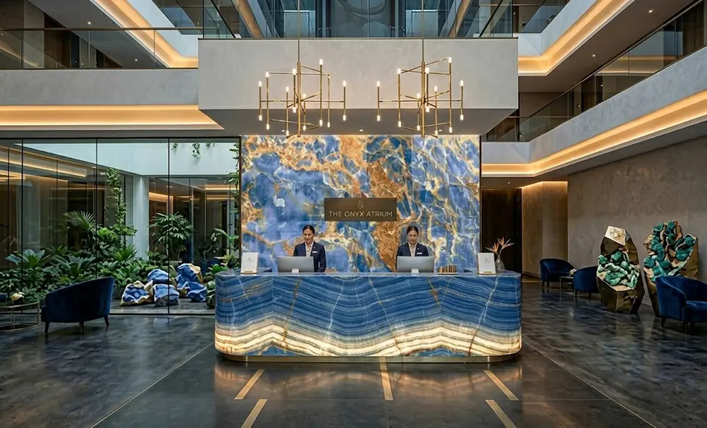 Luxury Hotel Lobby with Backlit Blue Onyx Reception Desk A 5-star hotel reception desk clad in illuminated Blue Onyx panels with seamless mitered edges.