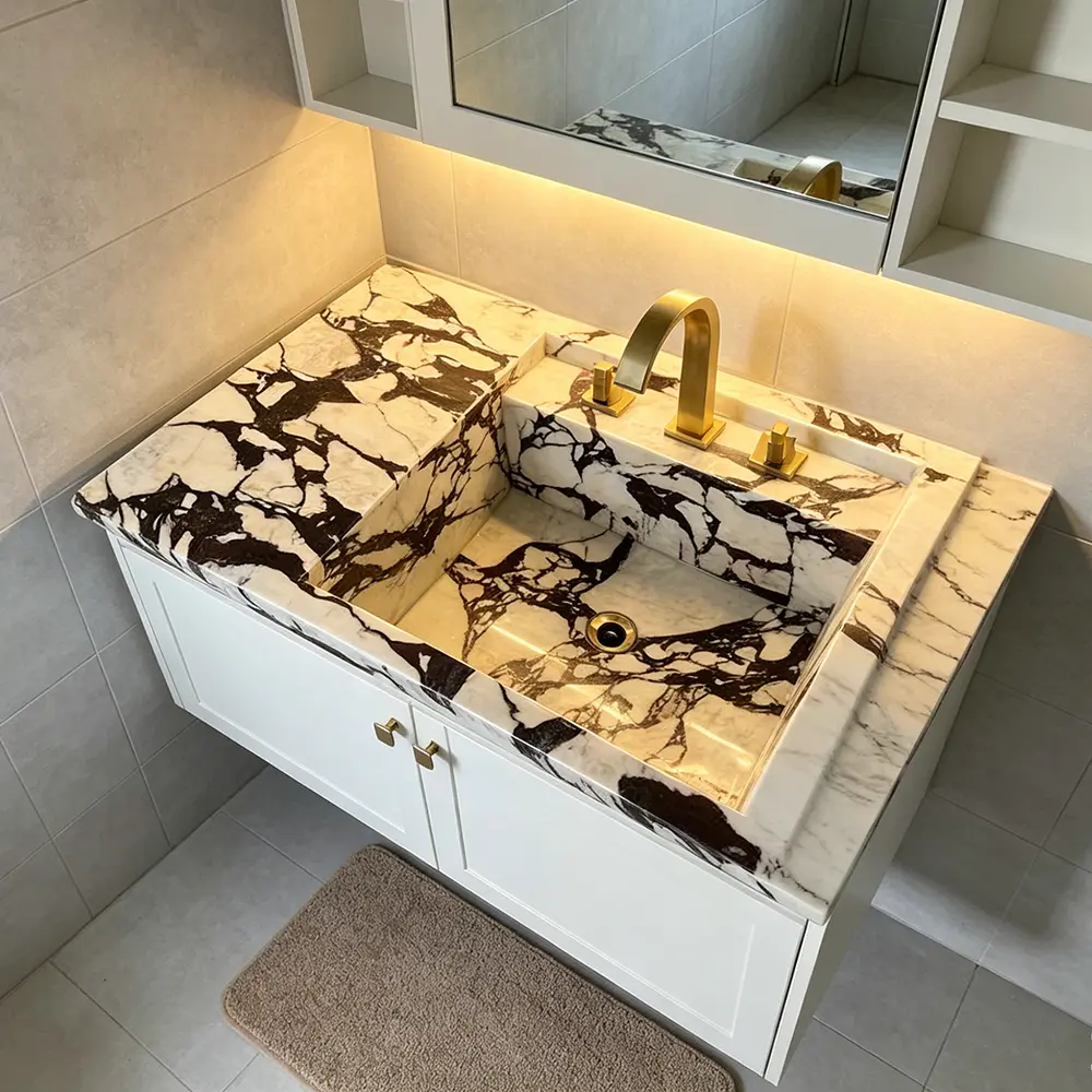 Bespoke Calacatta Viola Double Vanity Sink A luxurious master bathroom featuring a long, custom Calacatta Viola marble double vanity sink with dual brass faucets.