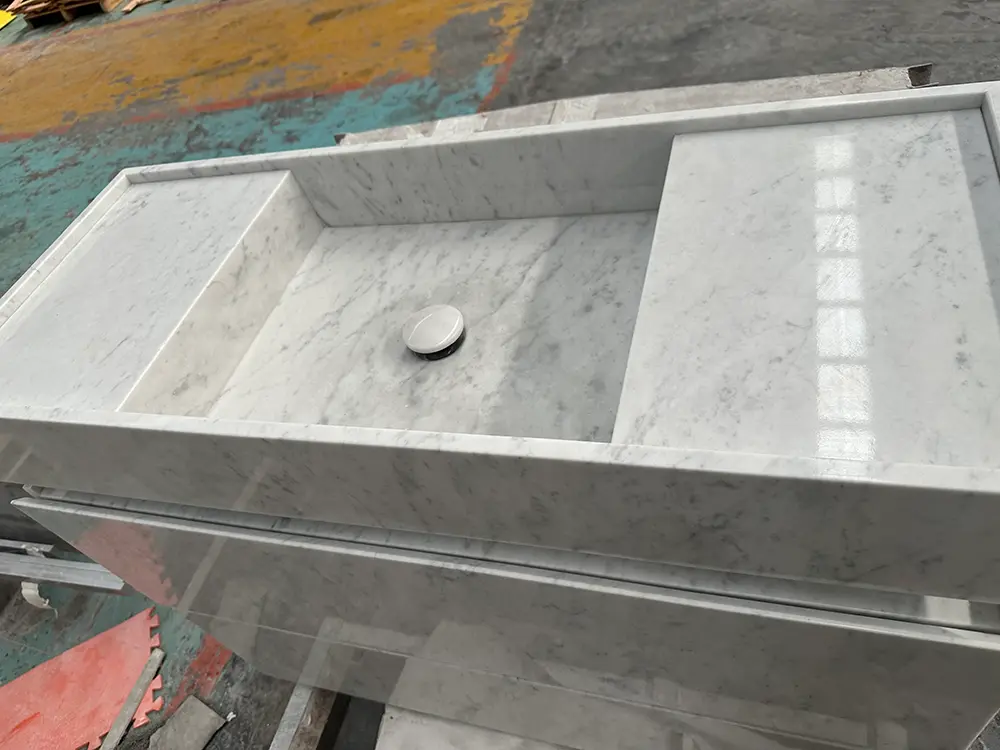 integrated-carrara-marble-sloped-sink-caron-stone Close-up technical shot of an integrated sloped sink basin precision-milled out of Carrara white marble, demonstrating perfect mitered corners.