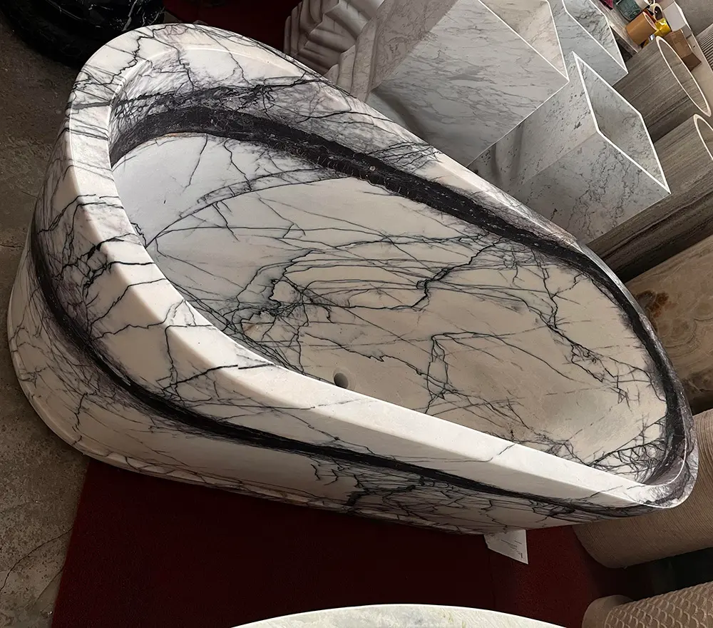 Styling Lilac Marble with Modern Hardware A sleek gunmetal black freestanding tub filler installed next to a heavily veined Lilac White marble stone bathtub.