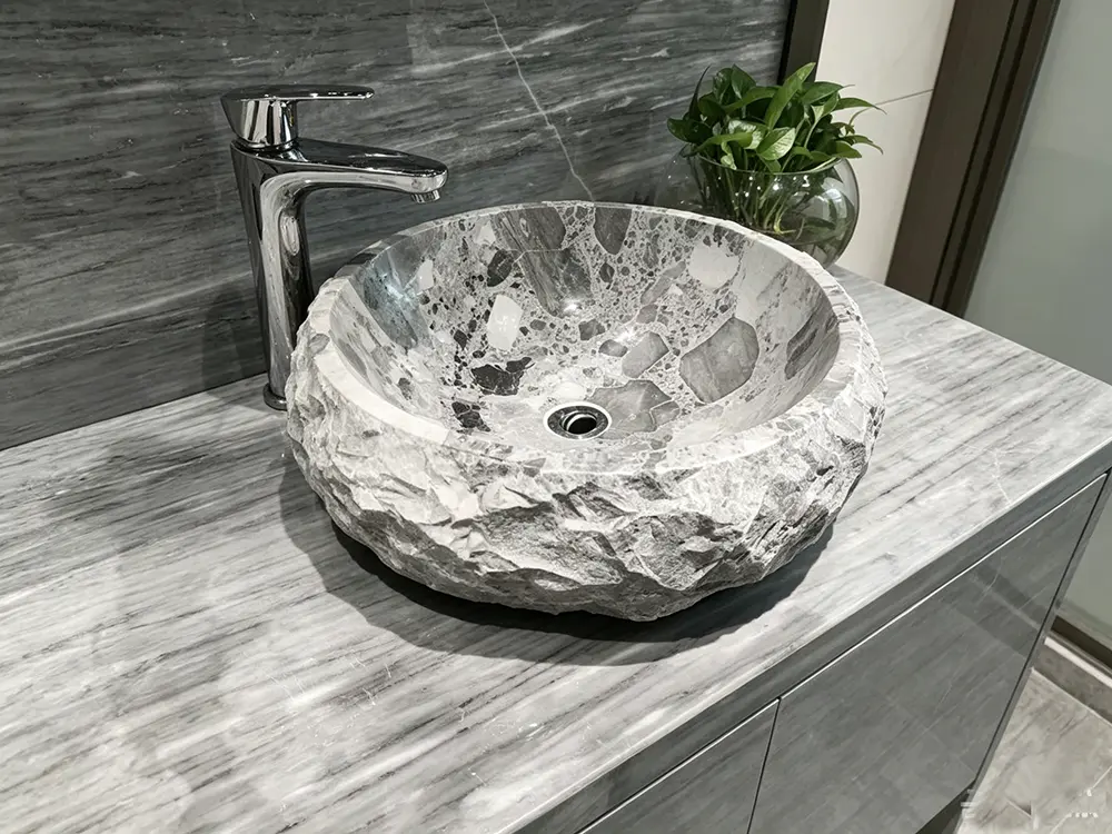 Vessel Sink and Hardware Styling Side profile of the chiseled Grigio Volcano marble vessel sink paired with a sleek, tall polished chrome deck-mounted faucet.