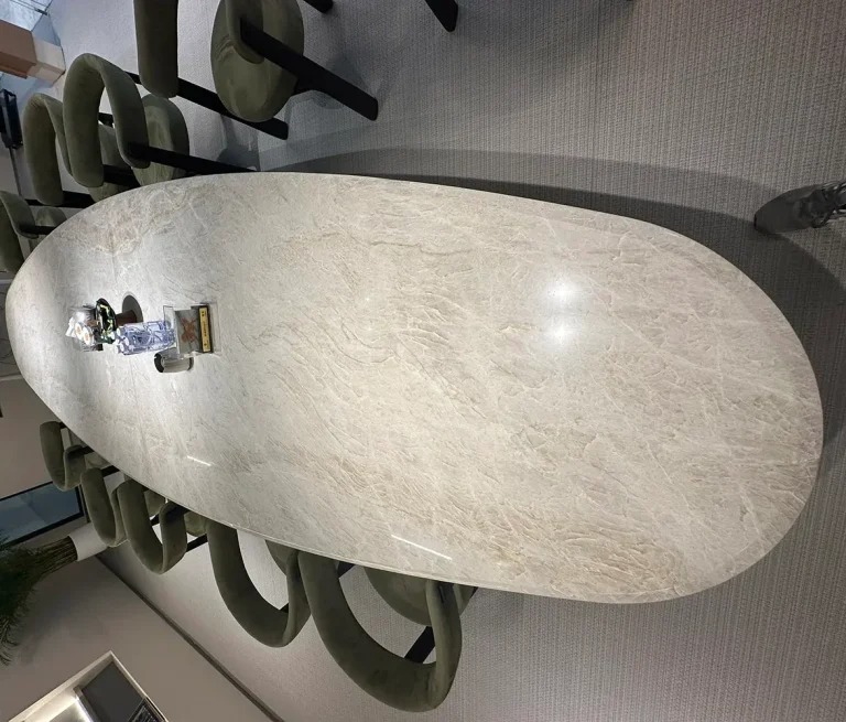 Large polished Taj Mahal Quartzite conference tables featuring natural beige and grey veining, surrounded by green upholstered chairs in a modern corporate meeting room.
